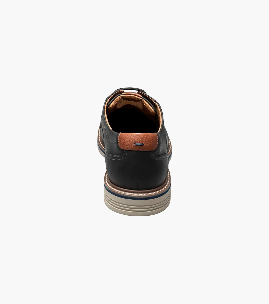 Black leather shoe with brown accents on a white background