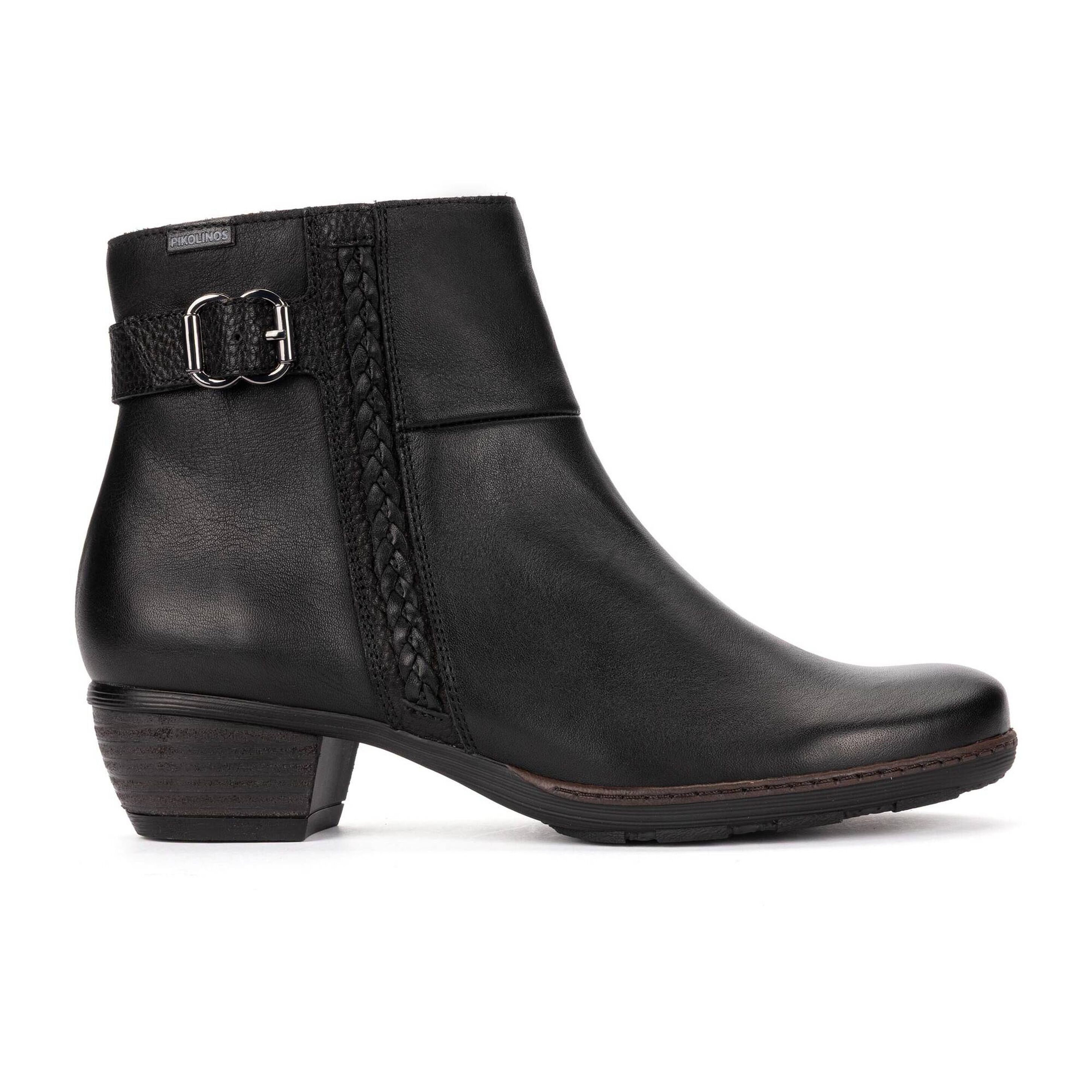 A black leather ankle boot with a low block heel, a decorative side strap with a silver buckle, and a braided side detail, shown against a plain white background.