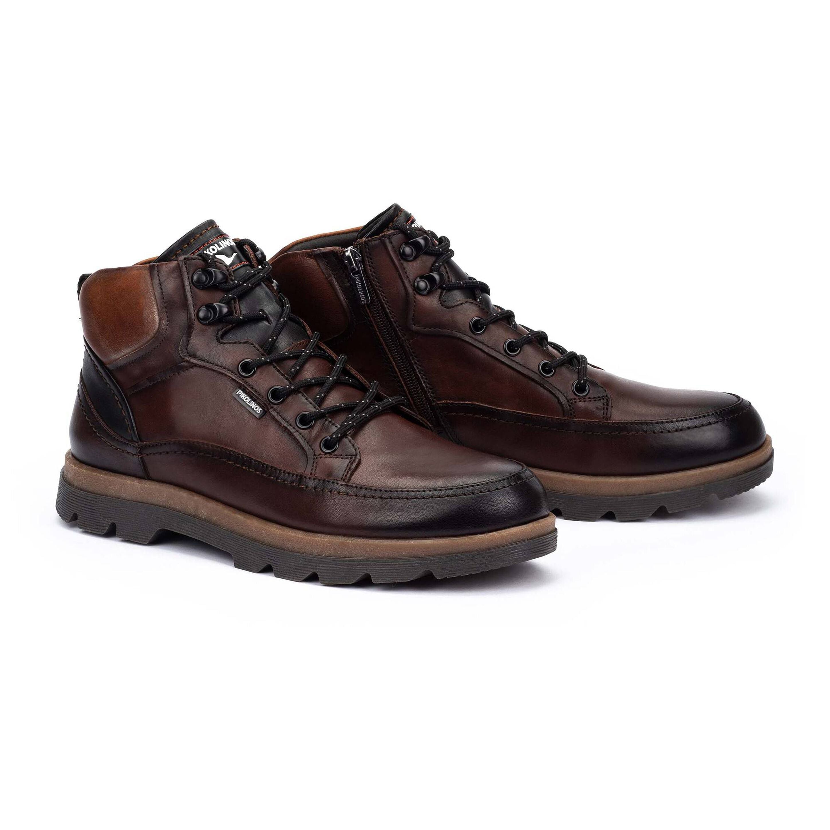 A pair of men's dark brown leather lace-up ankle boots with black laces, black side zippers, and rugged brown and black soles, shown on a white background.