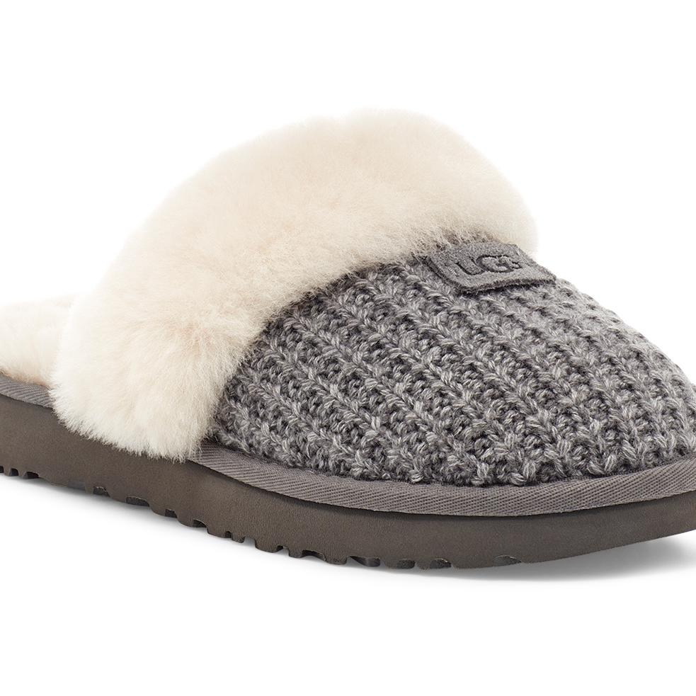 A single UGG slip-on slipper shown from a three-quarter angle on a white background. The slipper features a gray textured knit upper, a soft cream-colored shearling lining, and a dark brown sole.