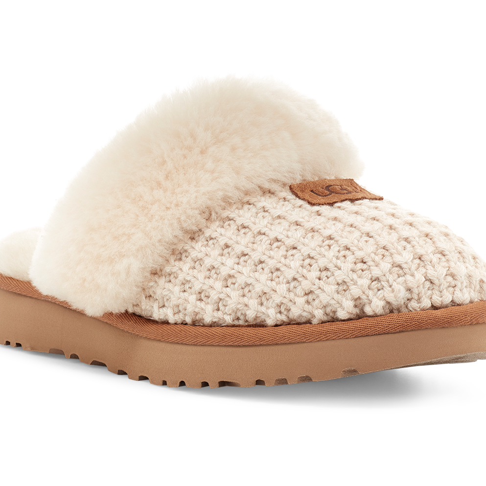A single slip-on slouchy slipper with a cream knit upper, fluffy cream shearling trim, and a tan sole, shown on a white background.