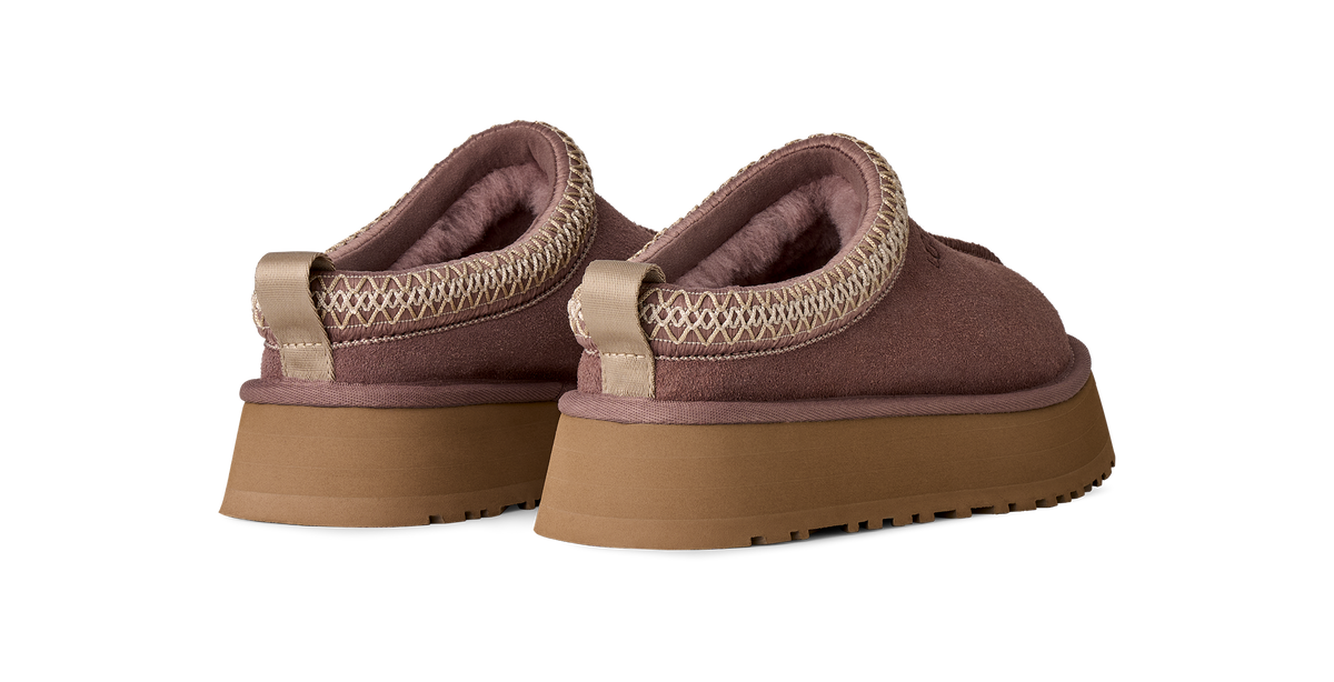 A pair of slip-on platform slippers in a dusty mauve-brown color, featuring a textured knit trim around the collar and a thick tan sole, shown against a plain white background.
