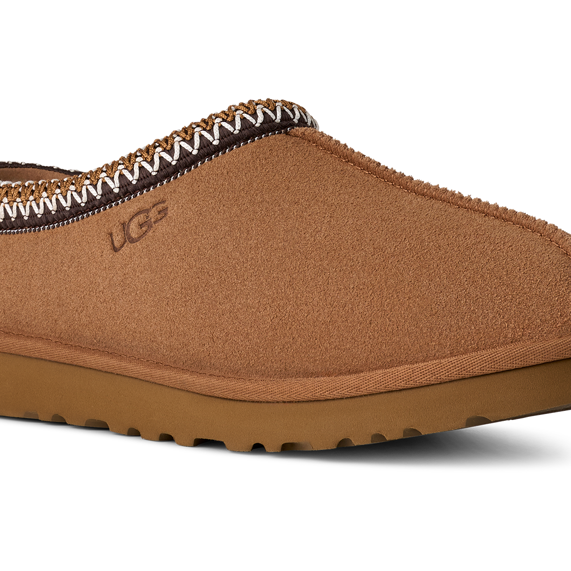 Brown UGG slipper with decorative trim on a white background