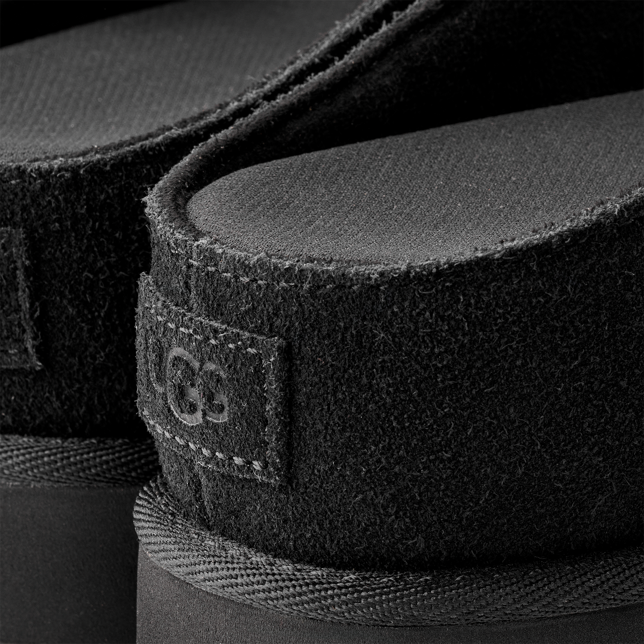Close-up of a black belt with a visible brand logo on a dark background