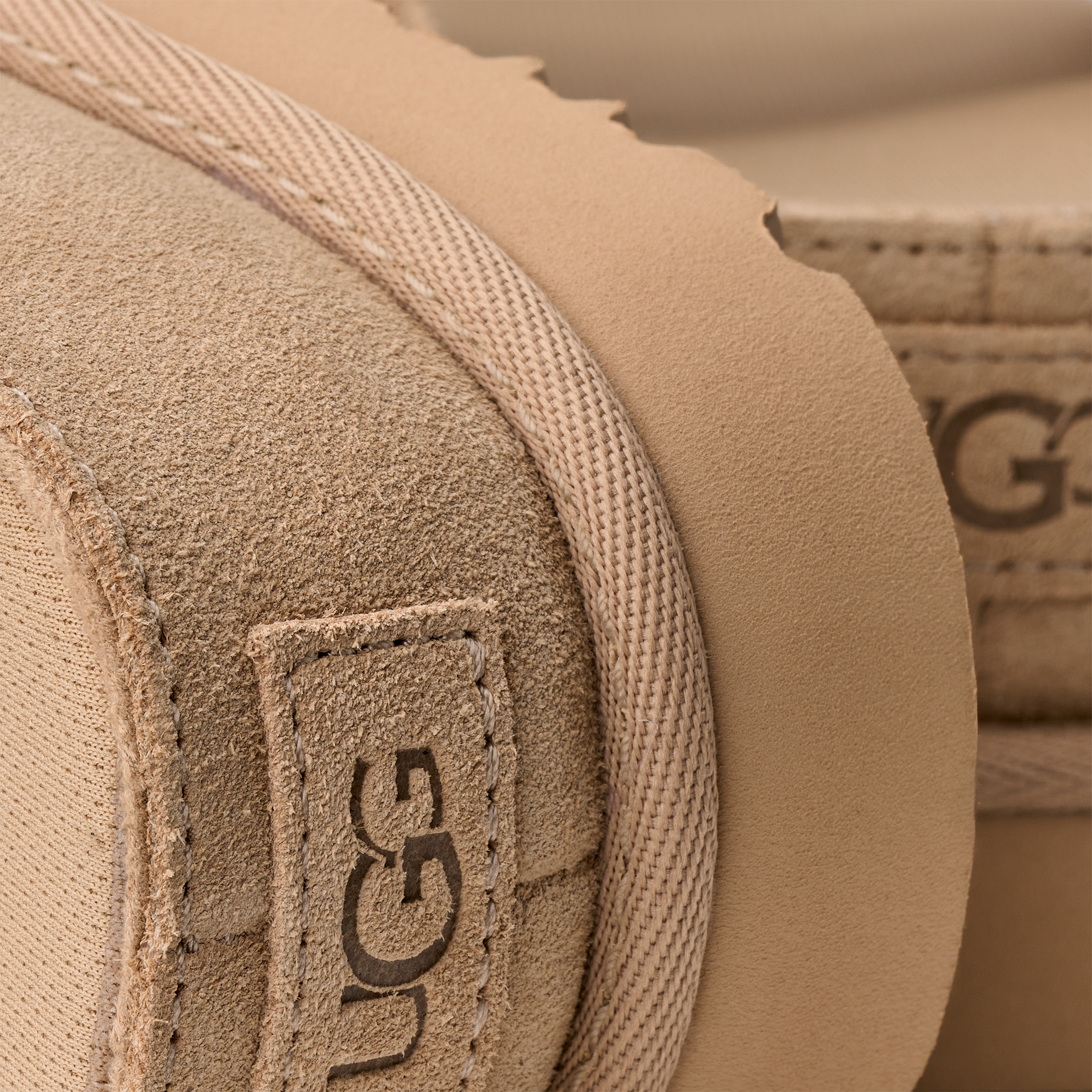 Close-up of a UGG logo on a tan fabric surface