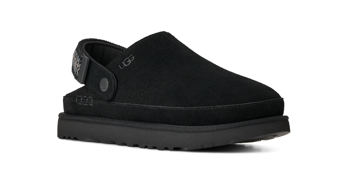 A black UGG slip-on clog shoe with a suede-like upper, a thick black platform sole, and a decorative heel strap with a silver-tone button closure, shown against a plain white background.