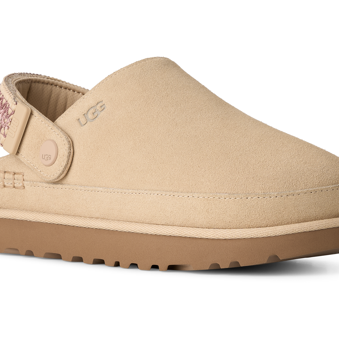 A beige UGG slip-on clog shoe with a tan sole, shown from a side profile on a white background.
