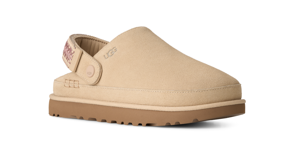 A beige UGG slip-on clog shoe with a tan sole, shown from a side profile on a white background.
