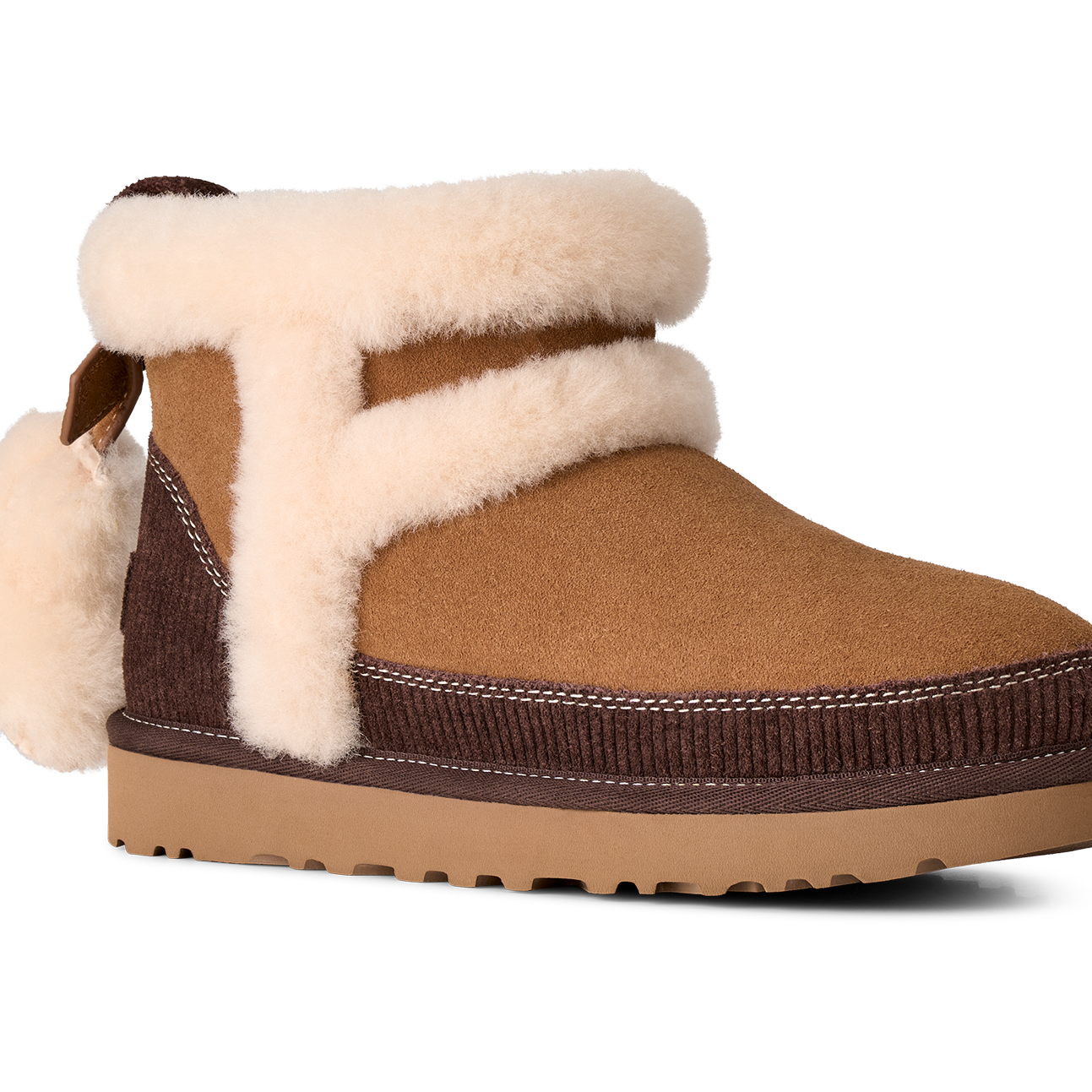 A brown suede ankle boot with thick cream shearling-style trim and a matching pom-pom, shown from a side profile on a white background.