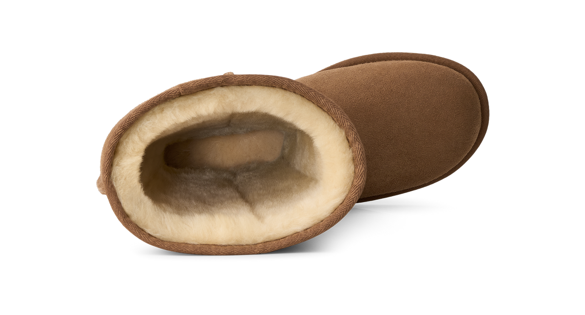 A pair of brown suede slipper boots with a soft cream-colored shearling lining, shown on a clean white background.