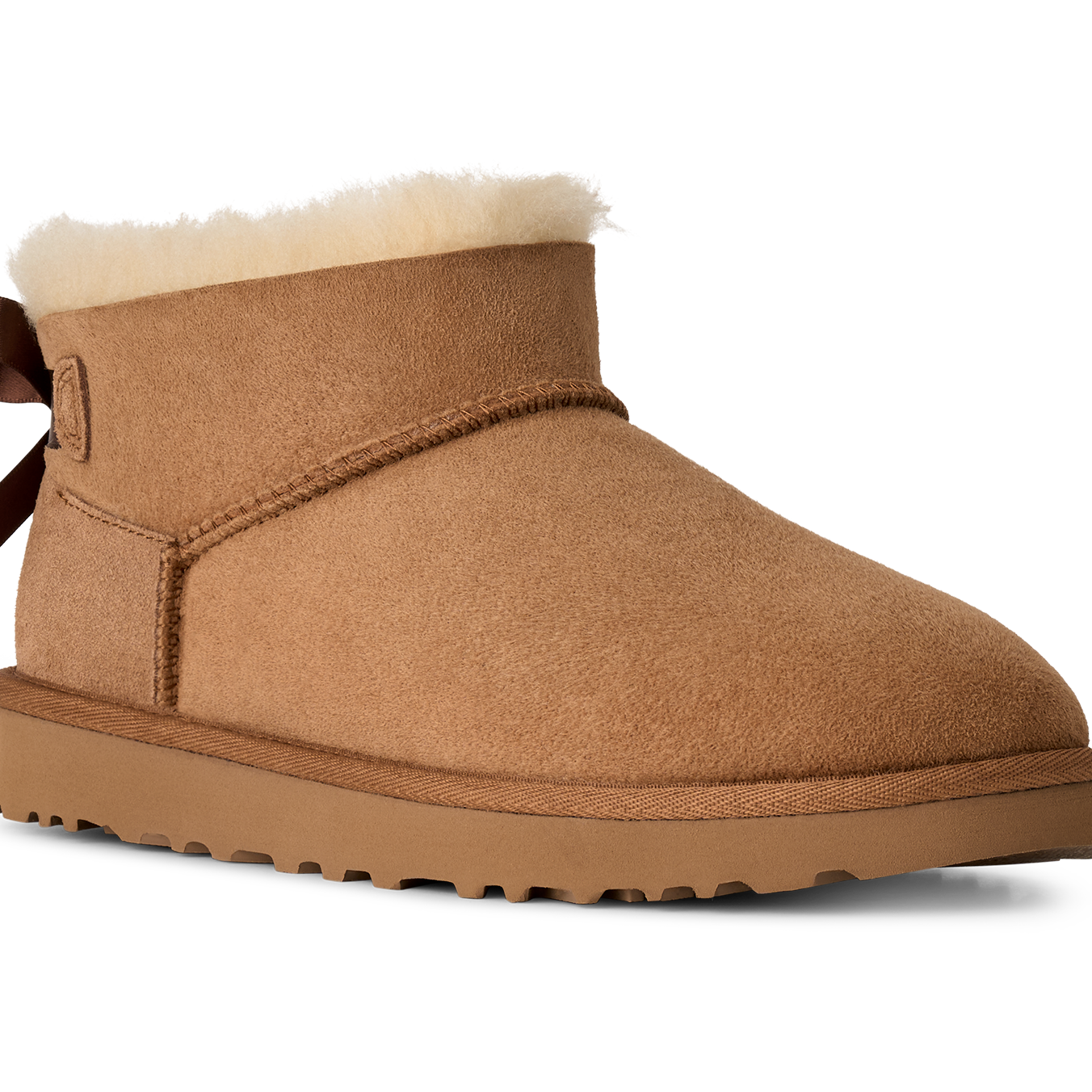 Tan suede boot with white fur lining and brown bow on a white background