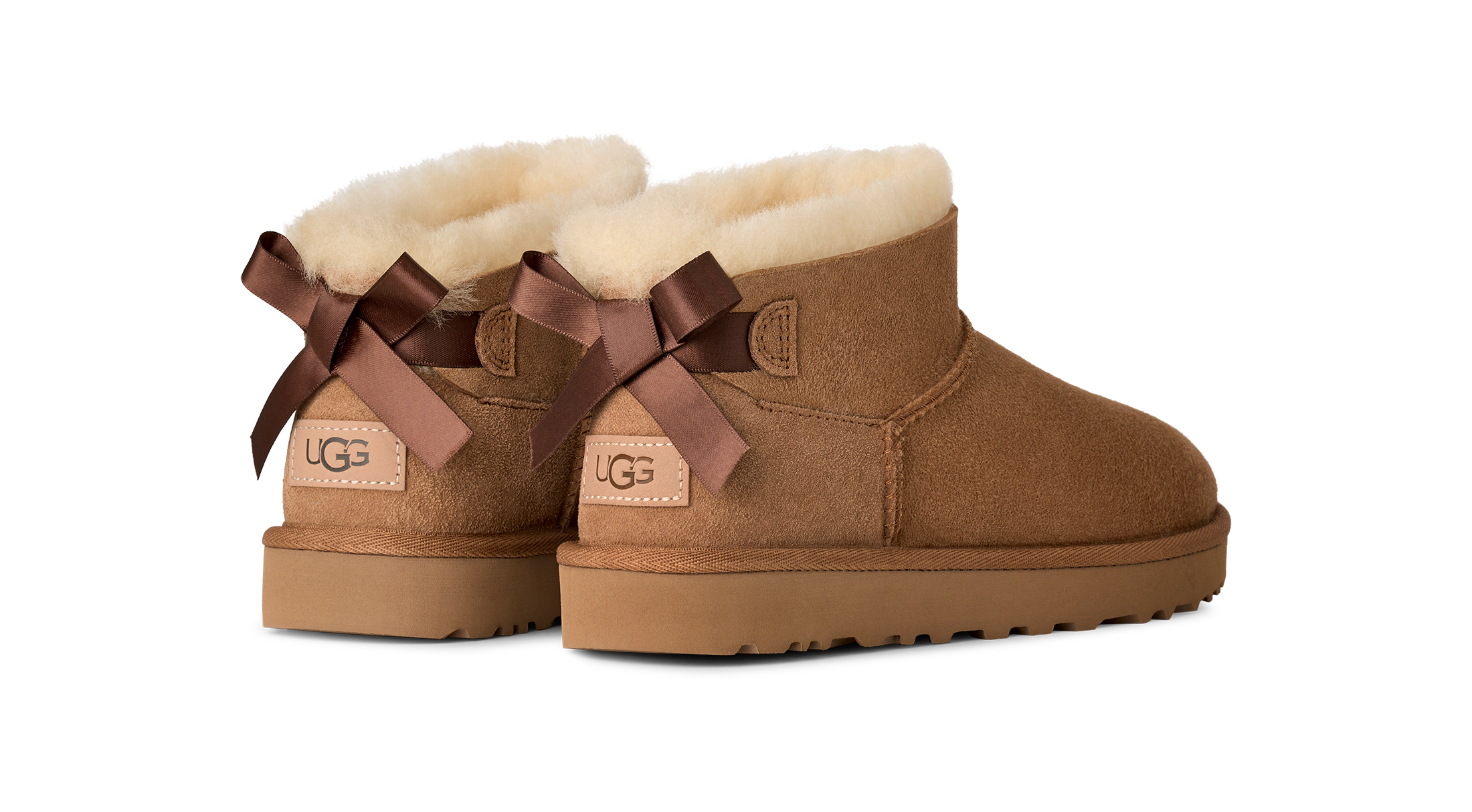 Pair of brown UGG boots with decorative bows on a white background