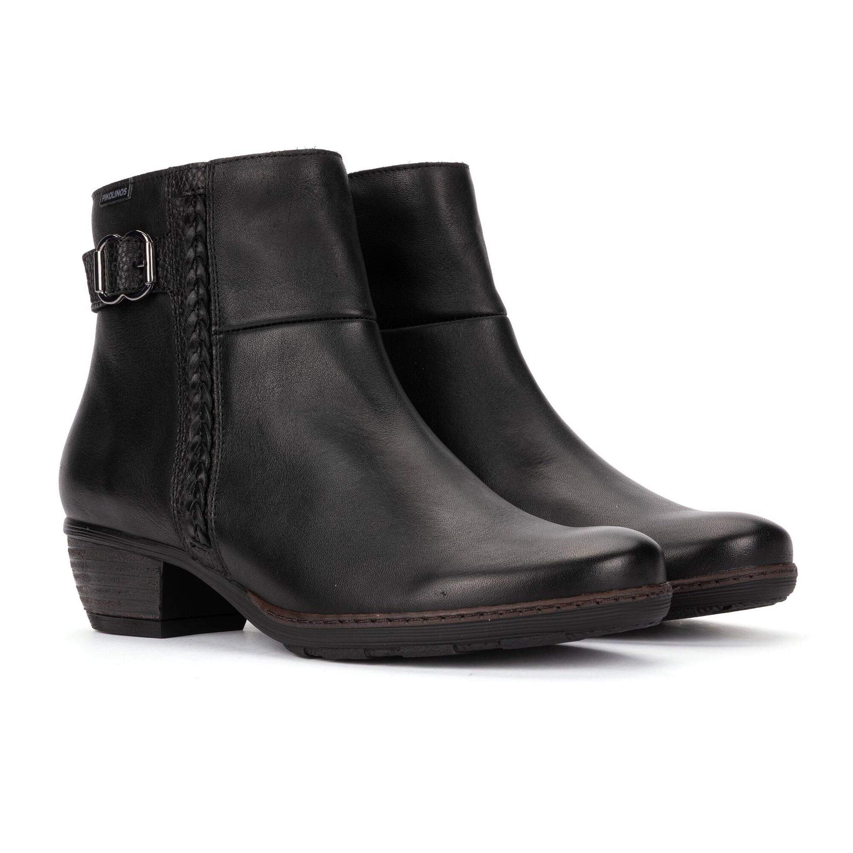 A pair of black leather ankle boots with a low block heel, braided side detail, and a silver buckle, shown on a white background.