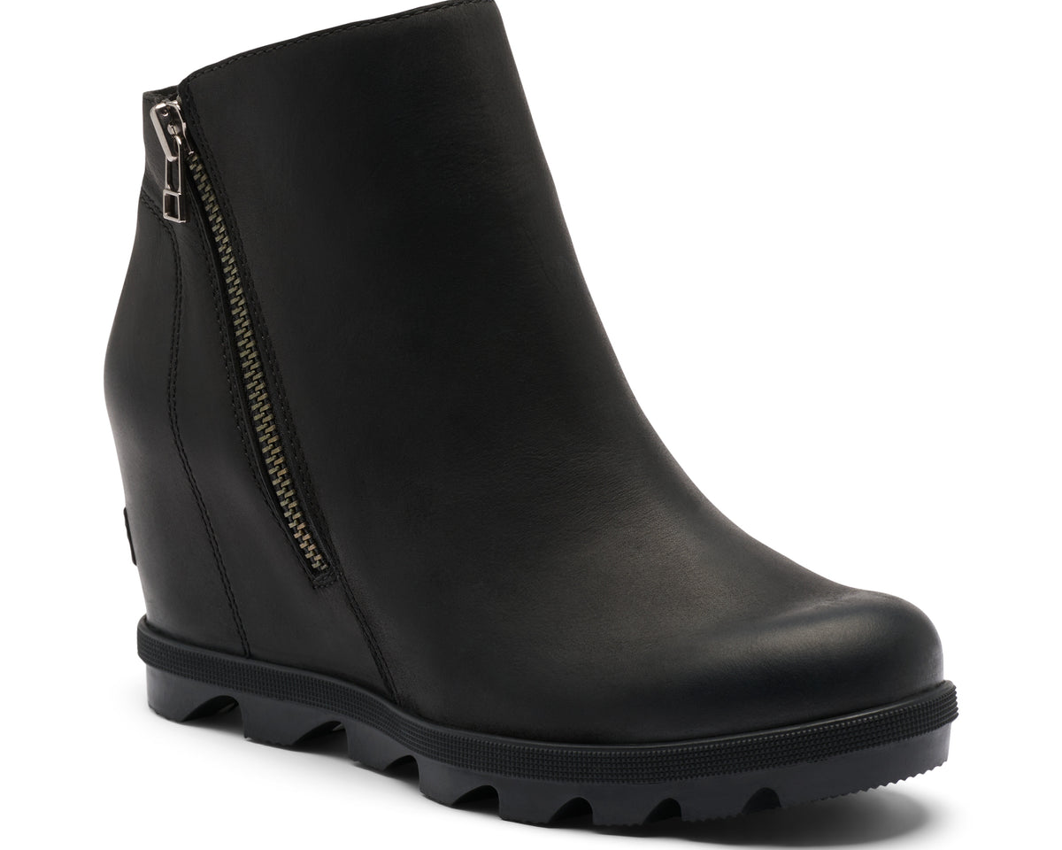 A black leather wedge ankle boot with a side zipper and a chunky lug sole, shown from a three-quarters angle on a white background.