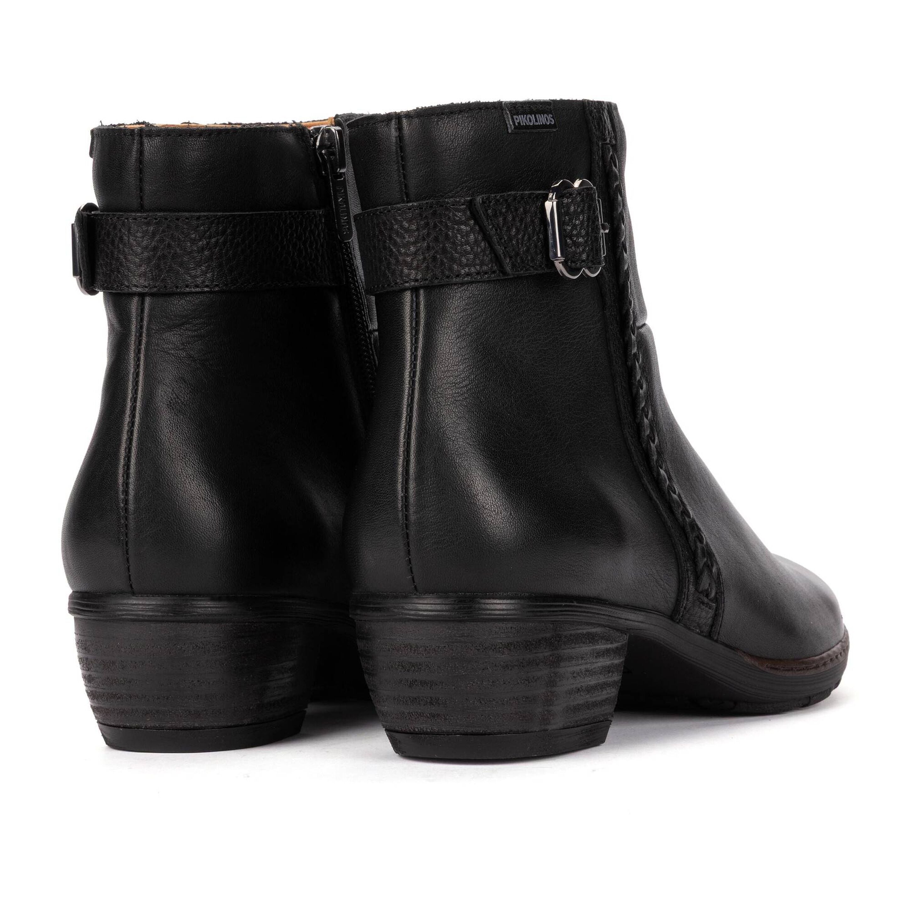 A pair of black leather ankle boots with side buckle straps and low block heels, shown from a rear three-quarter angle on a white background.