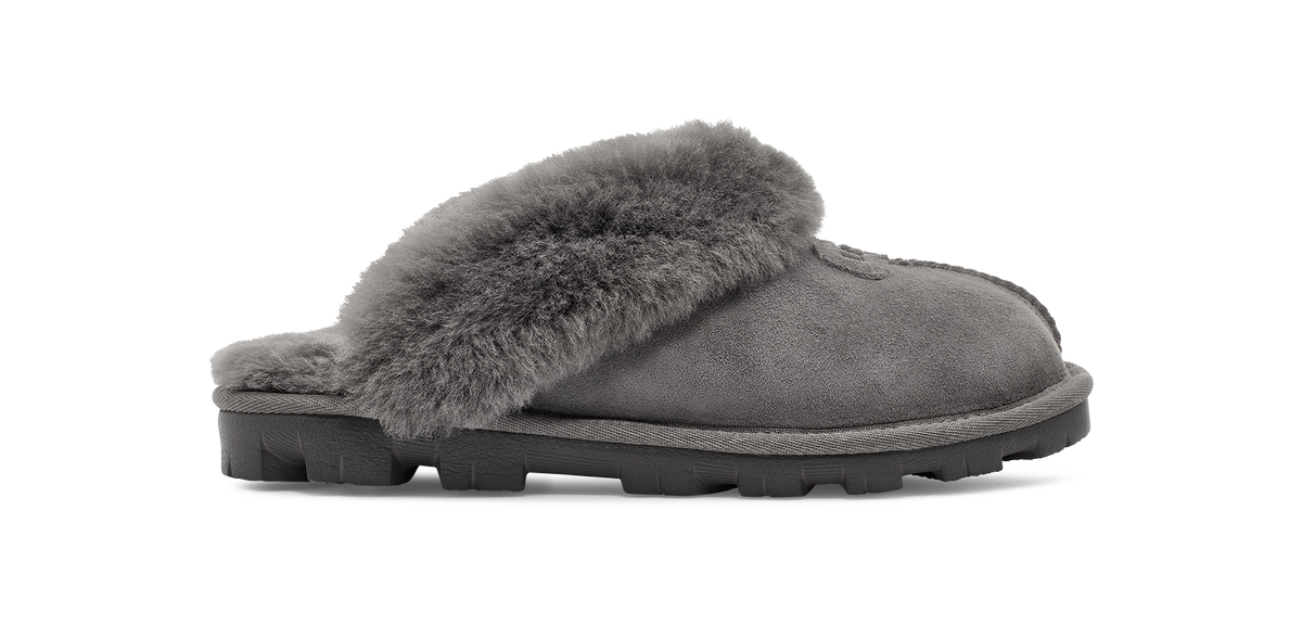 A single gray suede slipper with a thick gray faux-fur collar and a black lug sole, shown in profile against a white background.