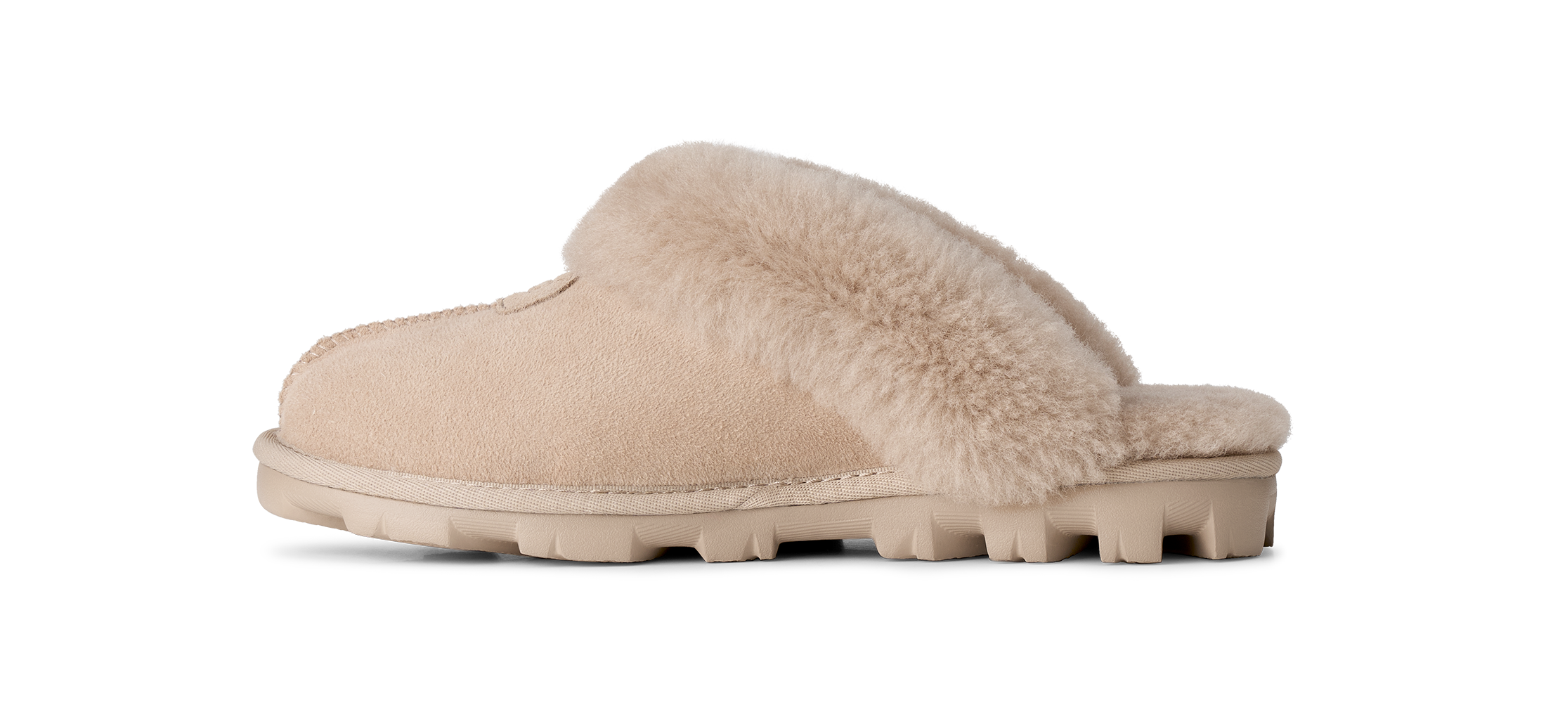 A single slip-on mule slipper in beige suede with a soft beige faux-fur collar and a chunky lug sole, shown in profile against a white background.