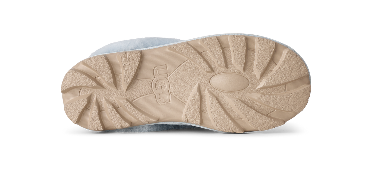 The beige rubber outsole of a UGG boot, showing the brand name embossed in the center, photographed from a top-down view on a white background.