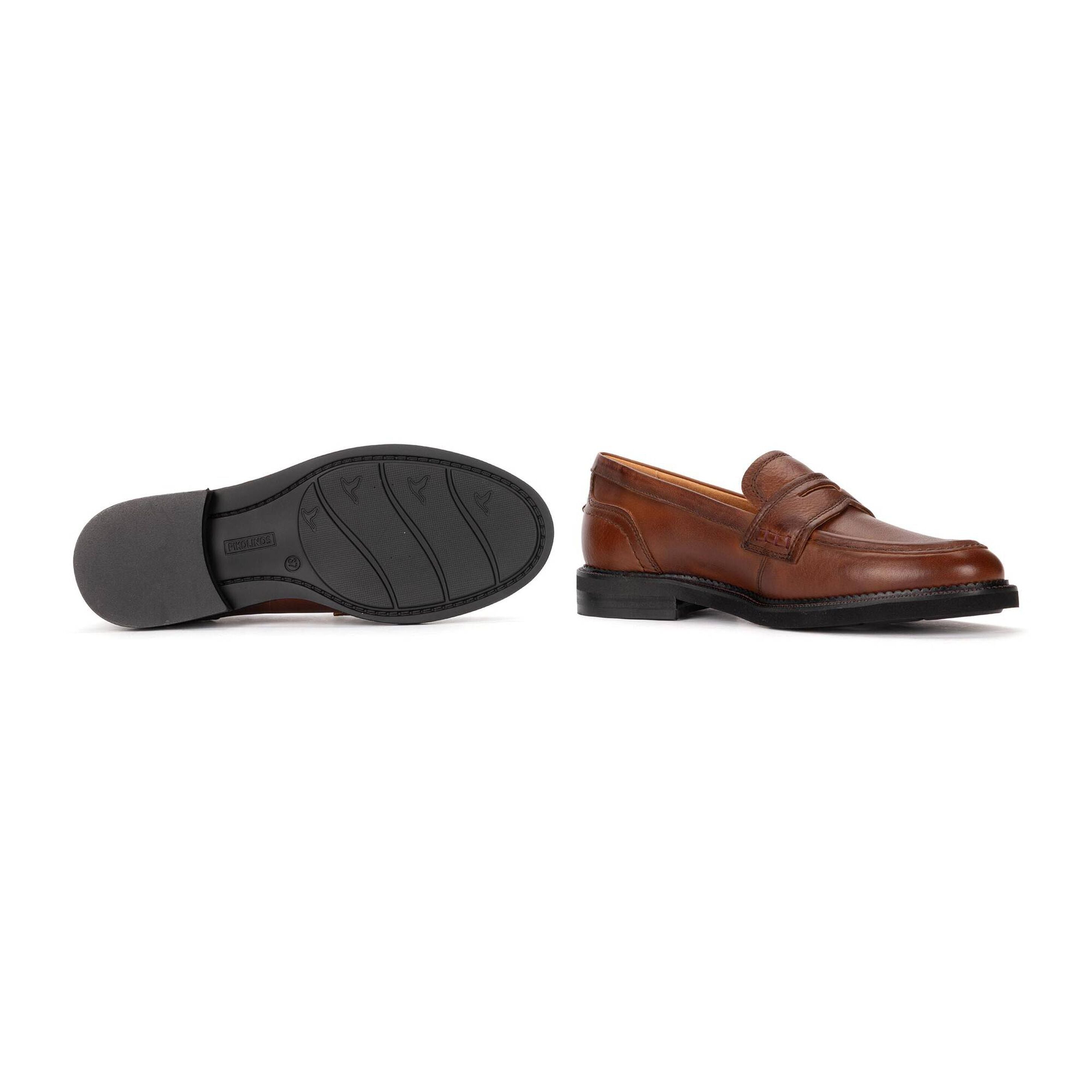 A pair of brown leather penny loafers shown on a white background, with one shoe displaying the side profile and the other showing the black outsole.