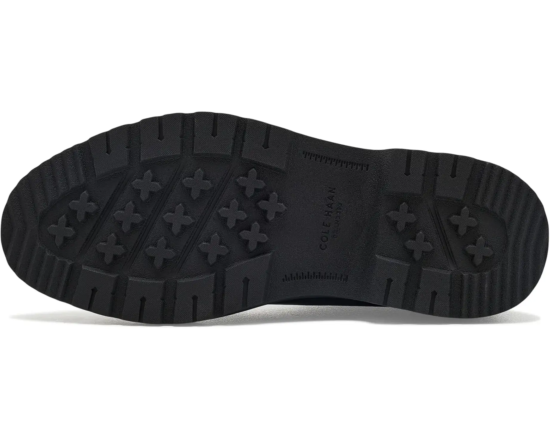 The black rubber outsole of a Cole haan shoe, showing the tread pattern and embossed brand name, photographed on a white background.