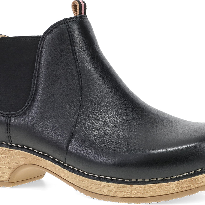 A black leather Chelsea boot with a natural wood-look stacked heel and contrast stitching, shown from a three-quarters angle on a white background.