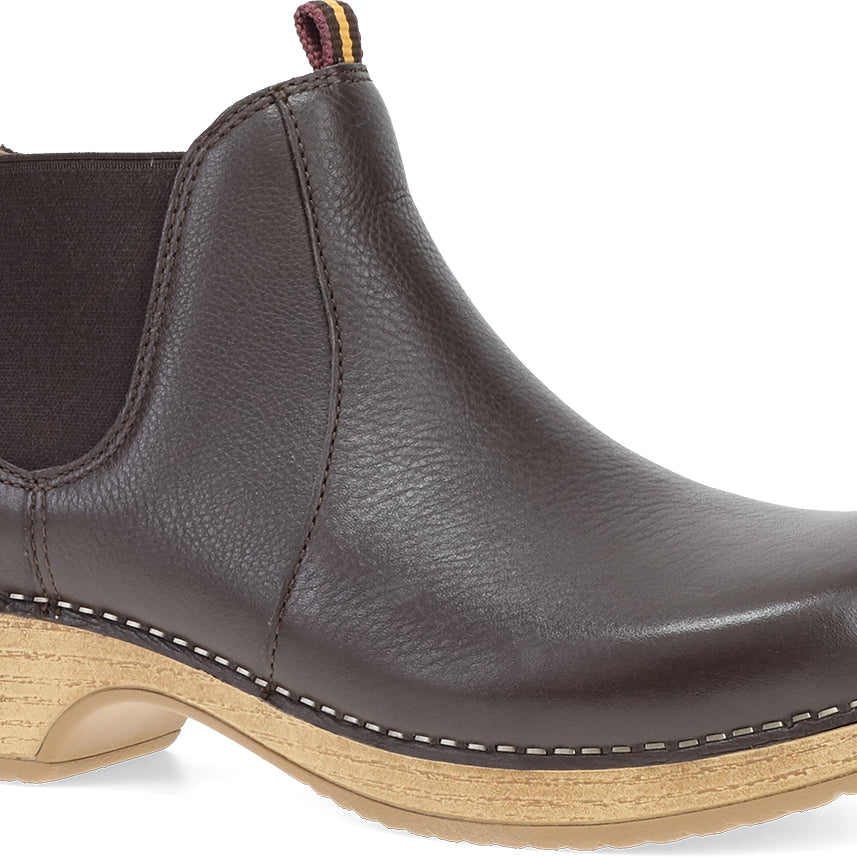 A black leather Chelsea boot with a natural wood-look stacked heel and contrast stitching, shown from a three-quarters angle on a white background.