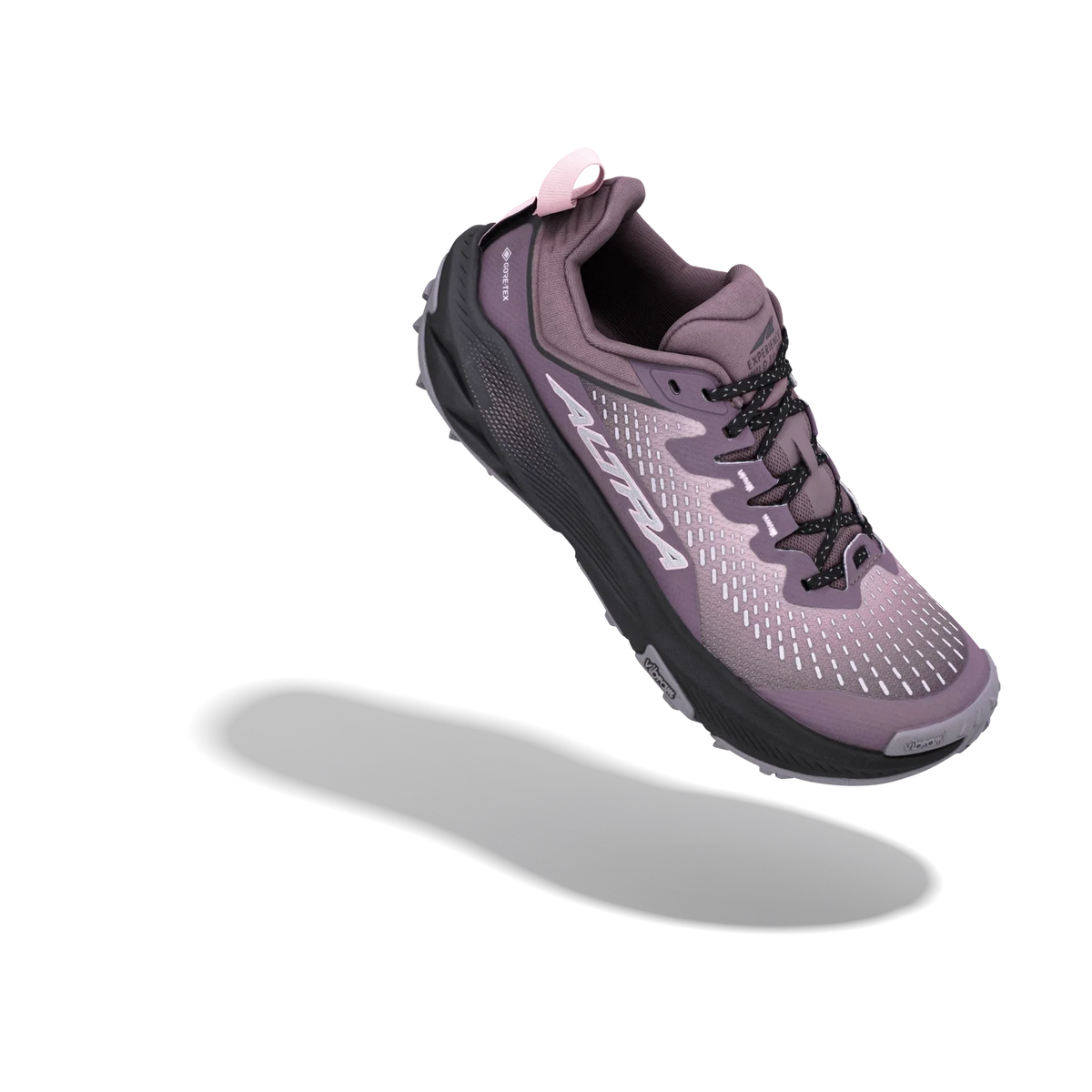 A single trail running shoe floating at an angle against a solid white background, featuring a purple and black colorway with a small pink pull tab.