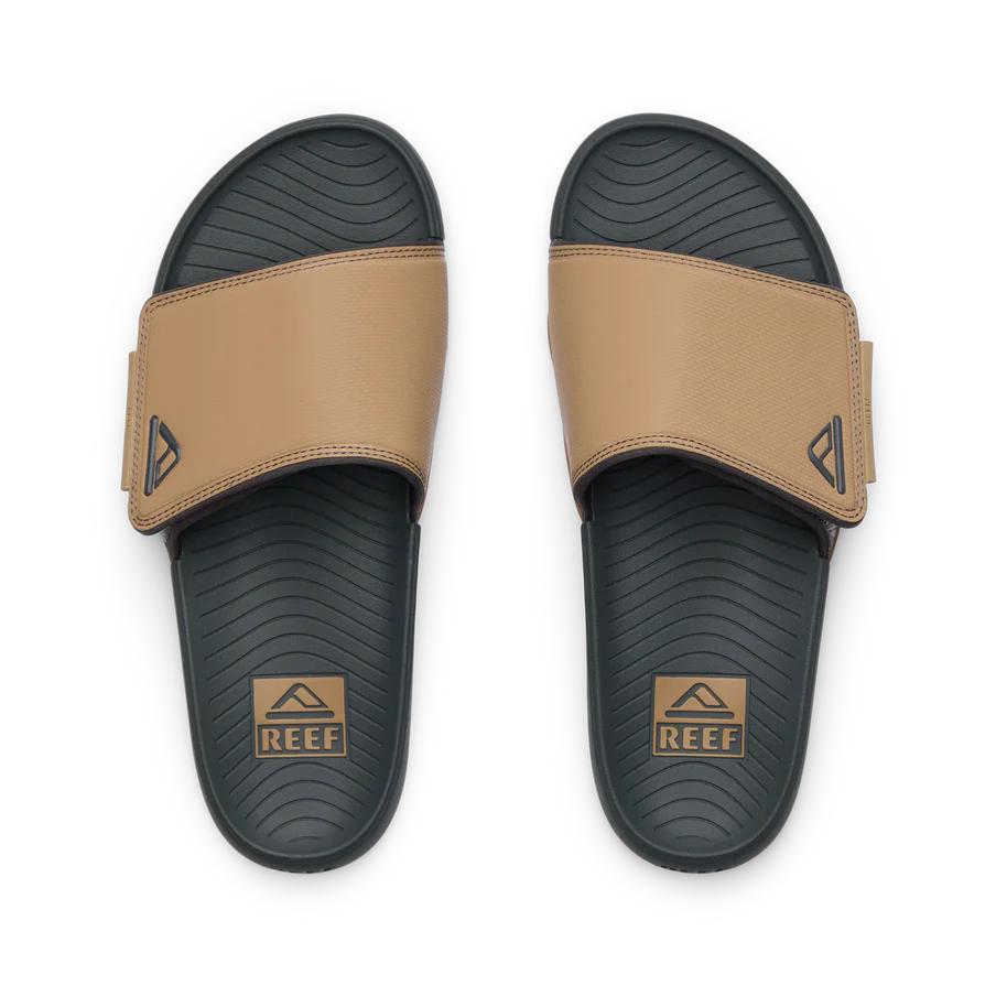 Pair of Reef sandals with tan straps and black soles on a white background