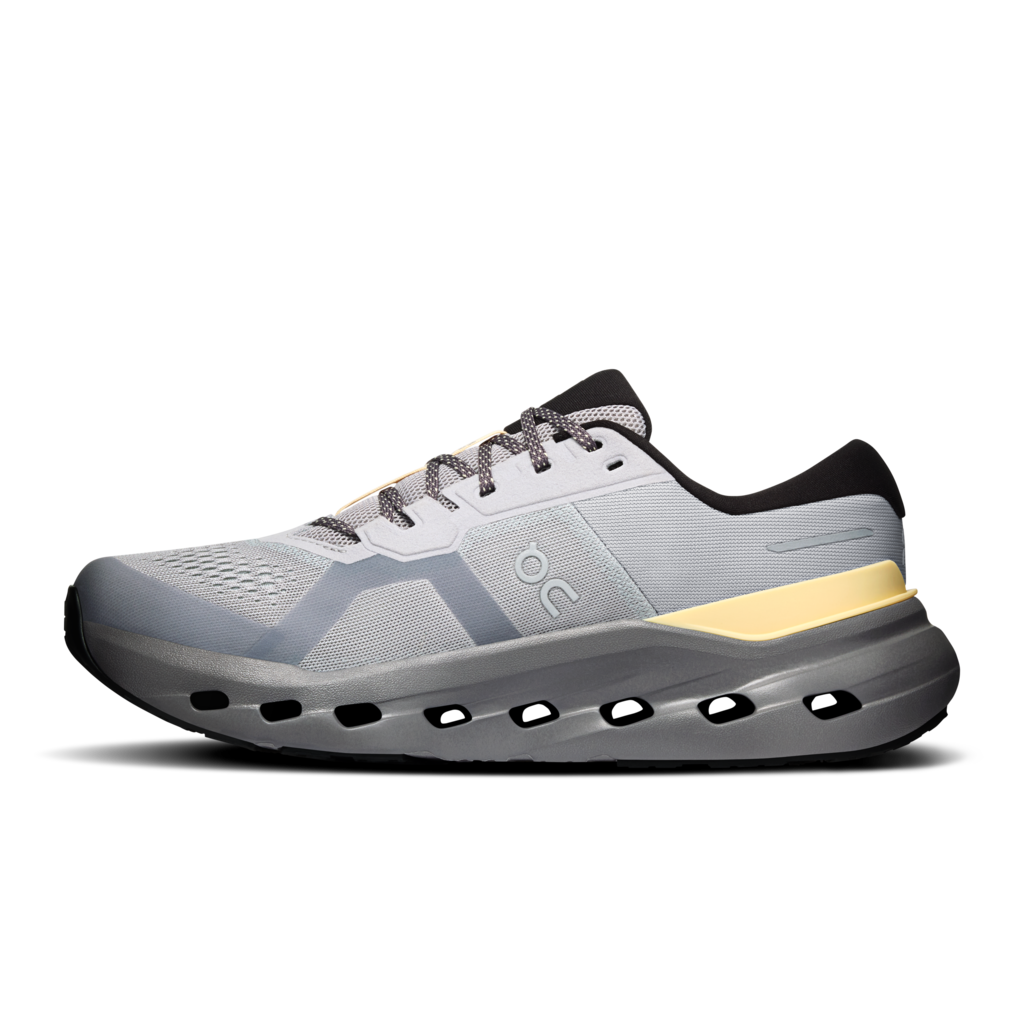 A light gray and white On running shoe with a black heel tab, gray laces, a yellow accent stripe, and a dark gray sole with cutout details, shown from a side profile on a white background.