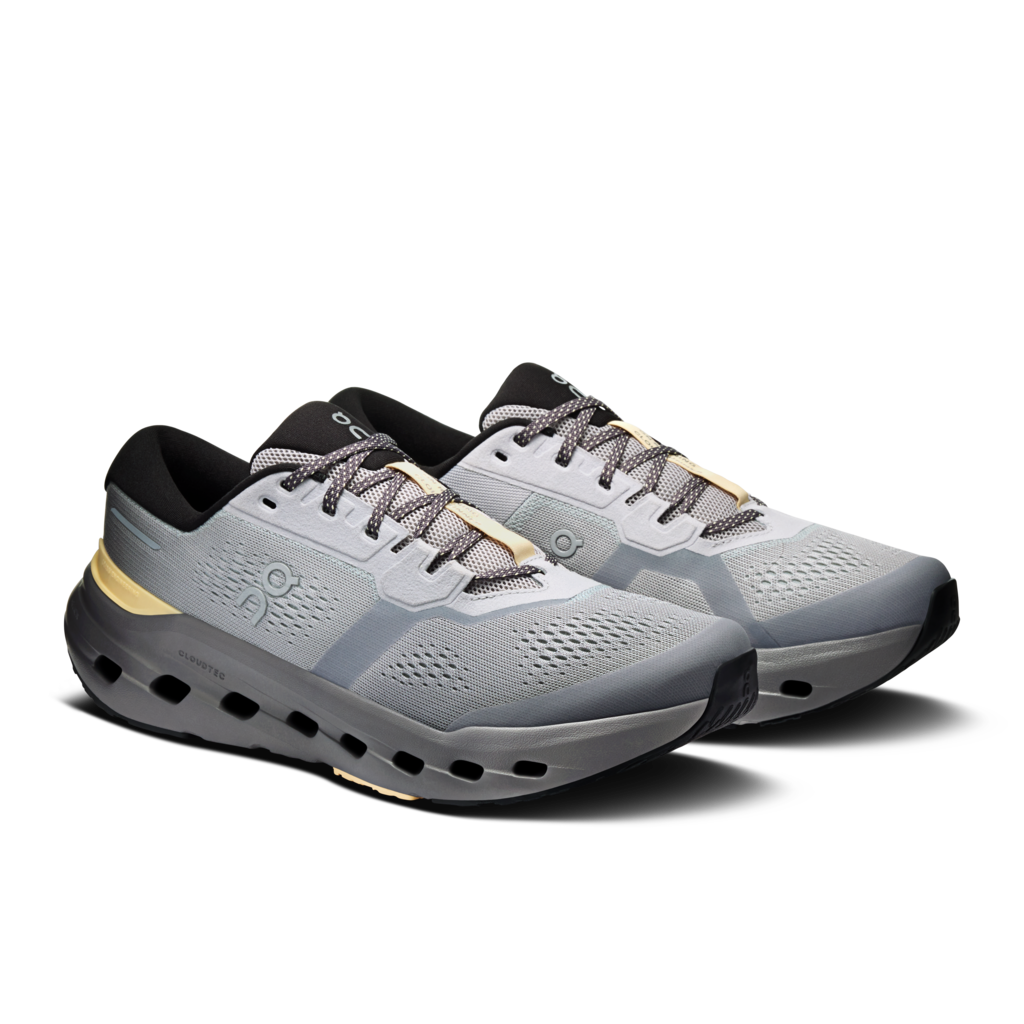 A pair of running shoes in light gray and dark gray with black and gold accents, shown from a three-quarters angle on a white background.