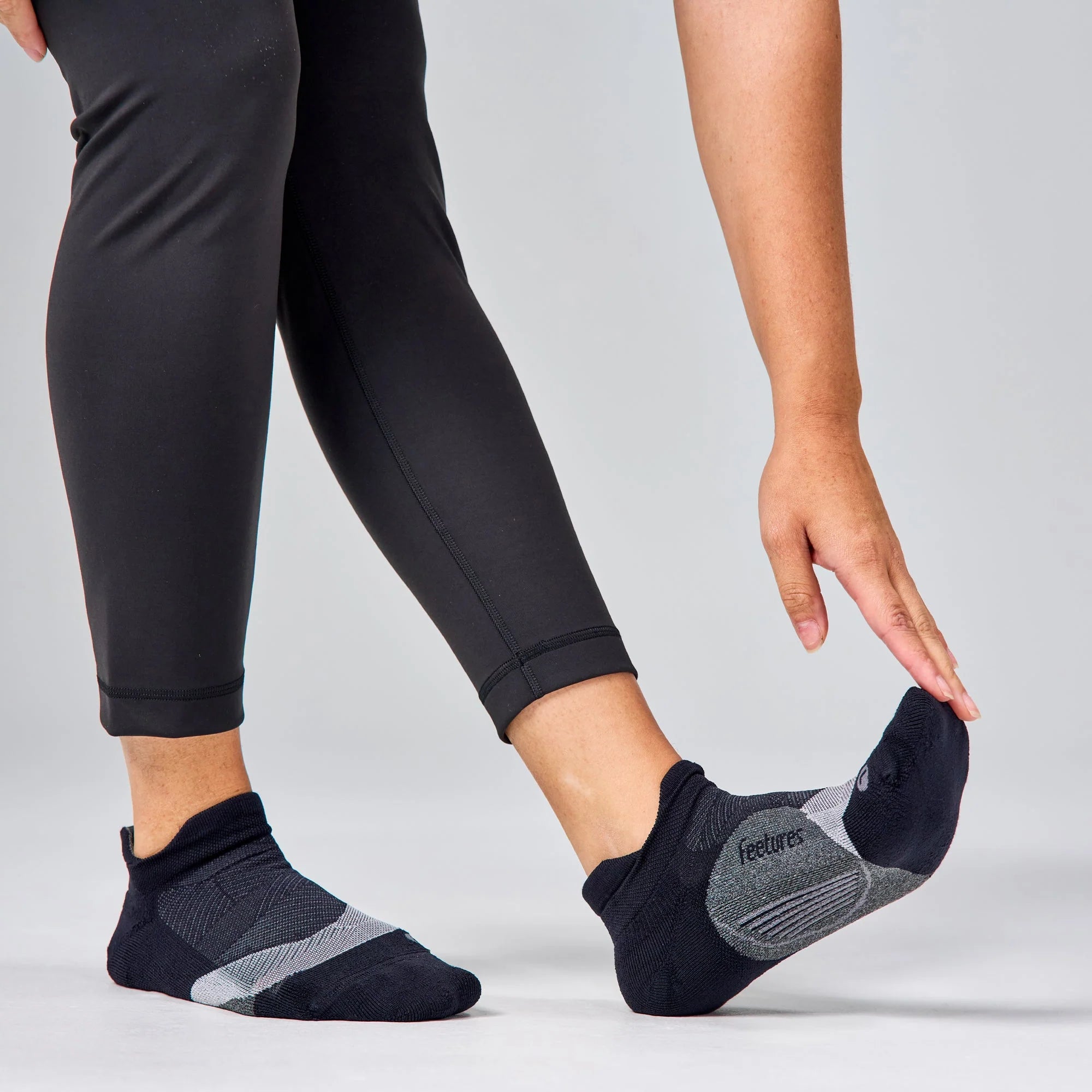 Person wearing black ankle socks with gray accents on a light gray background