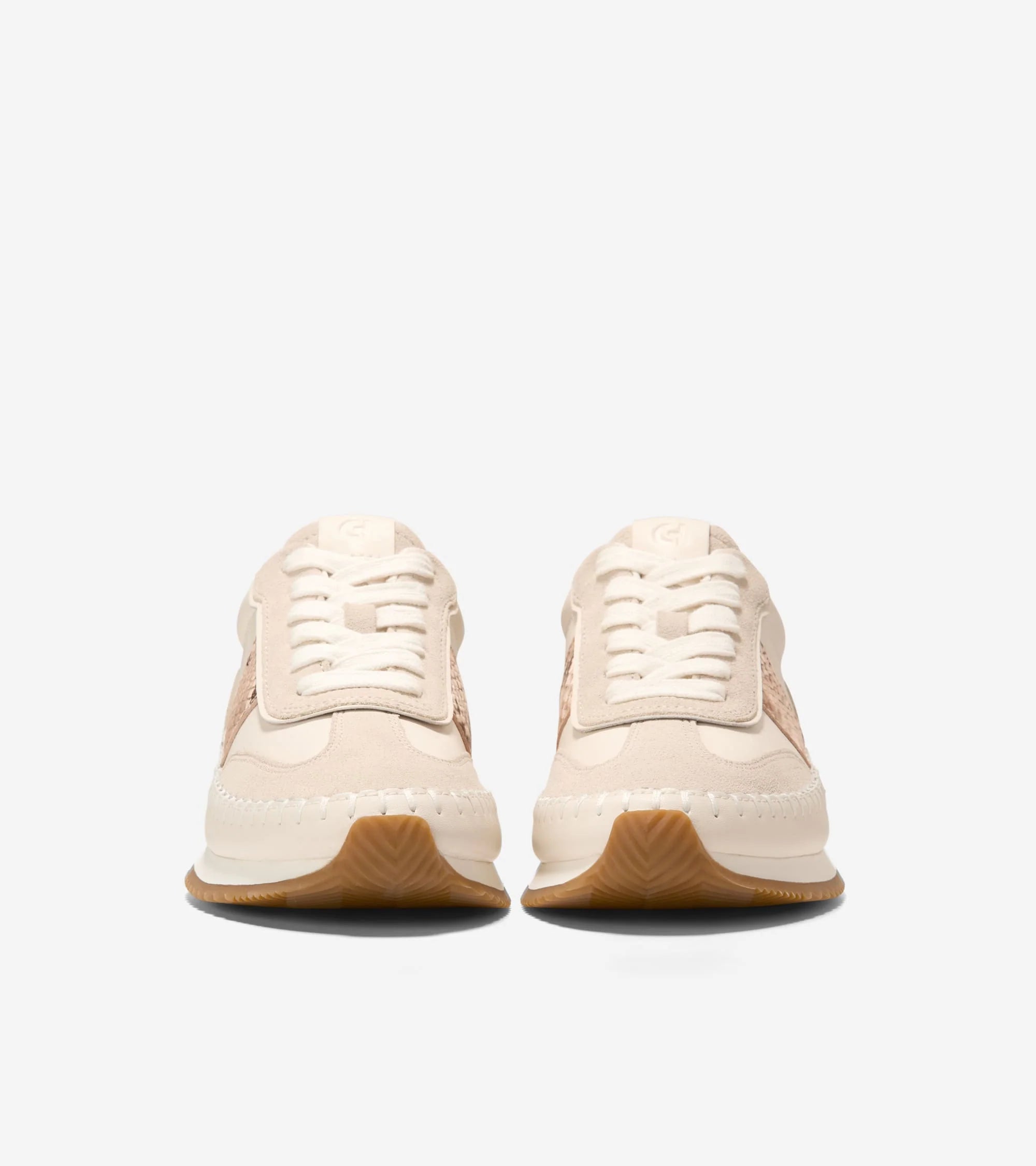 Pair of beige sneakers with brown soles on a white background