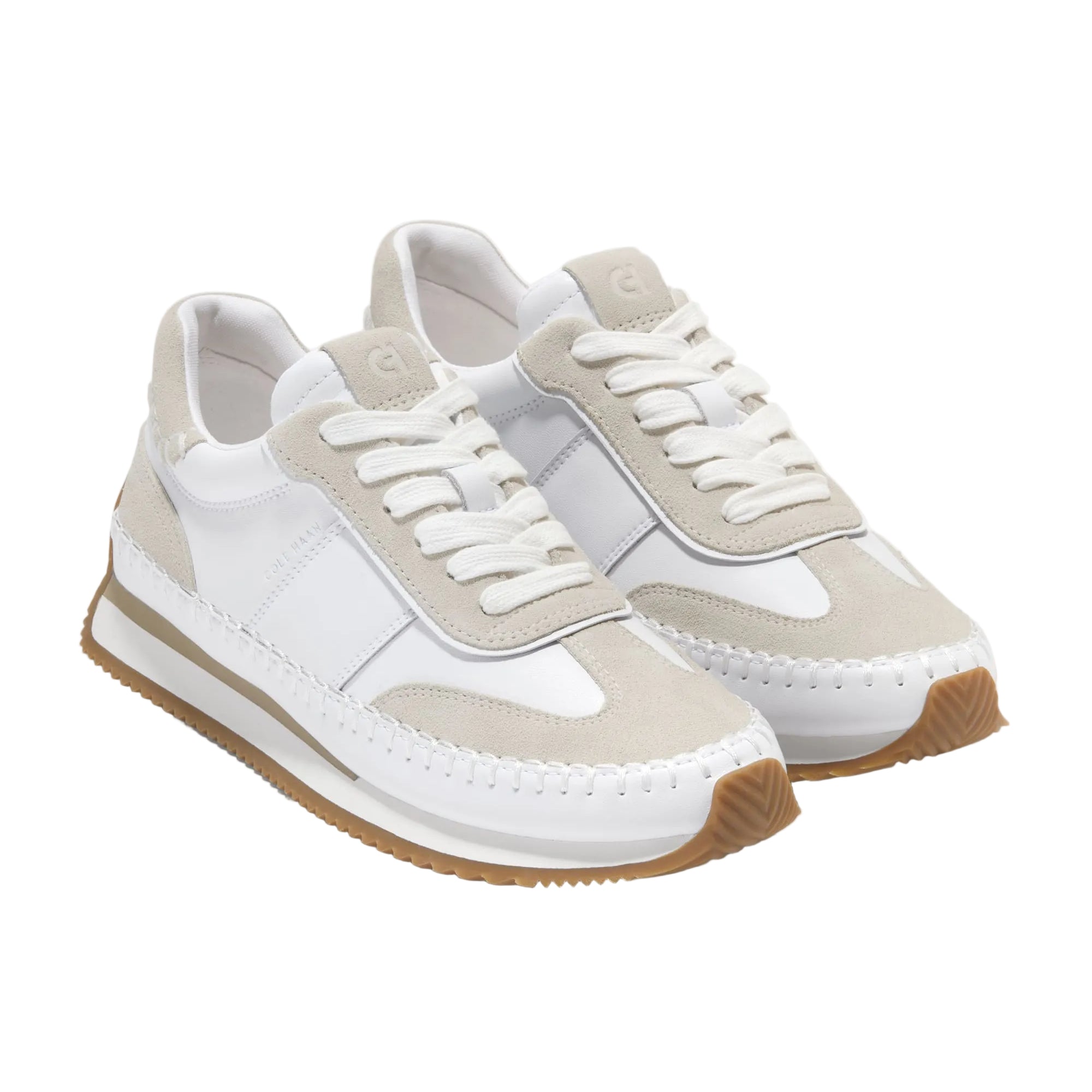 White and beige sneakers with brown soles on a light gray background