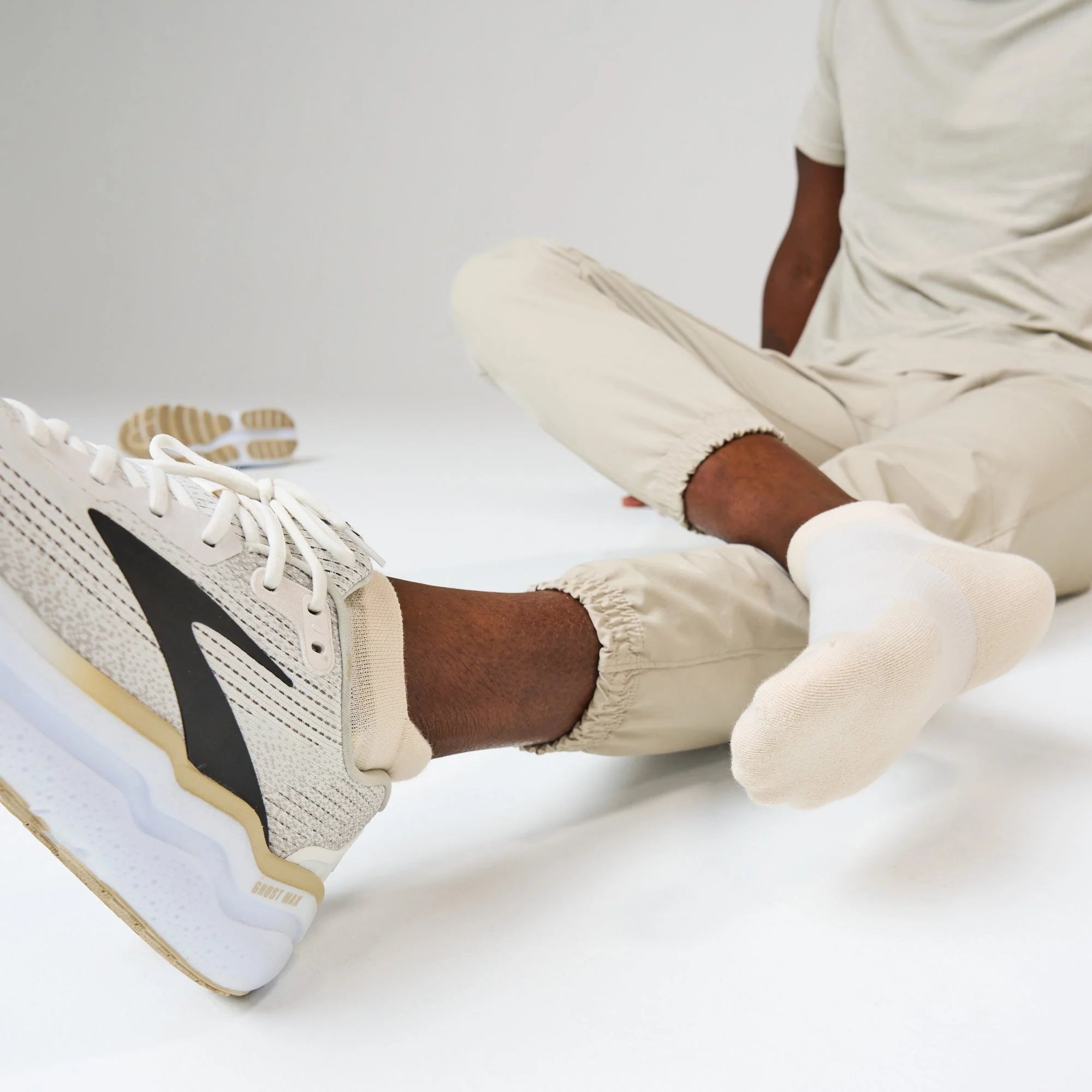 Person wearing beige sneakers with a black logo on a white background