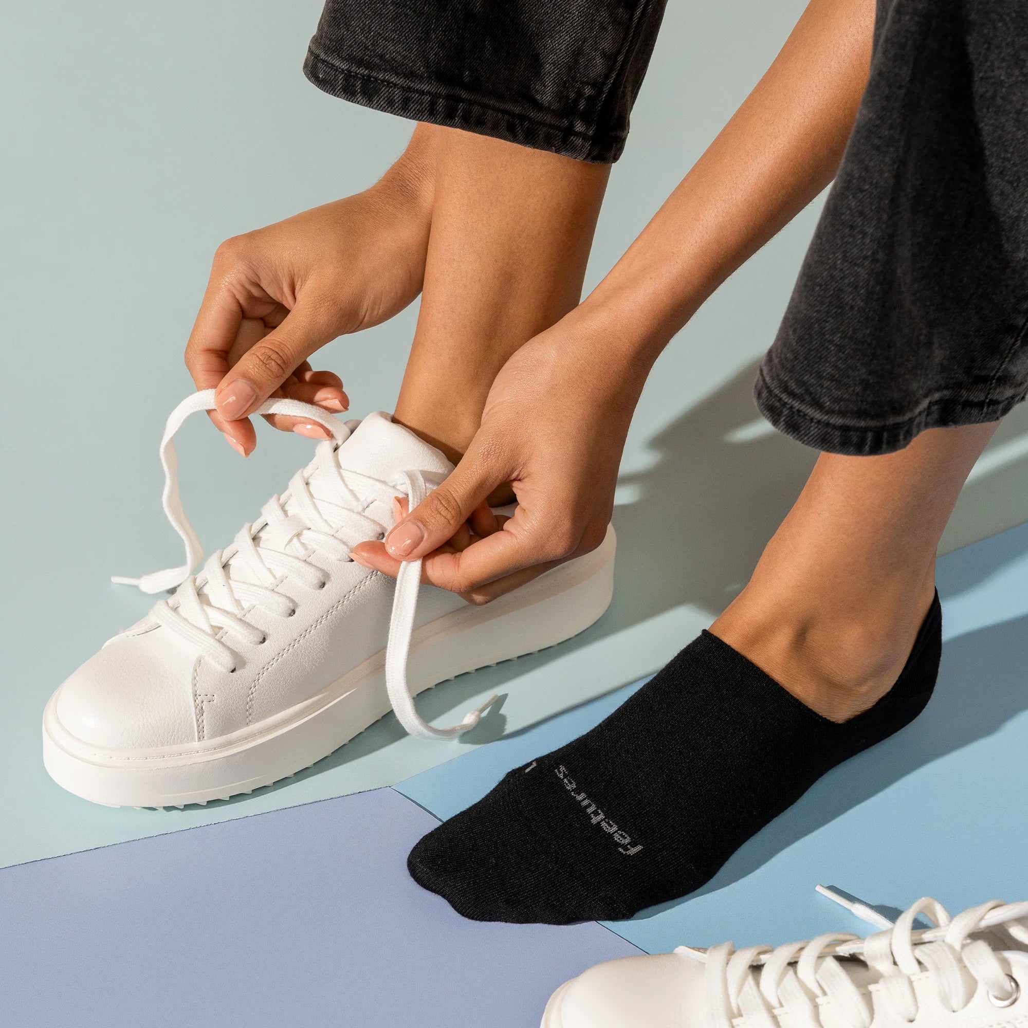 Person wearing black socks and white sneakers on a colorful background