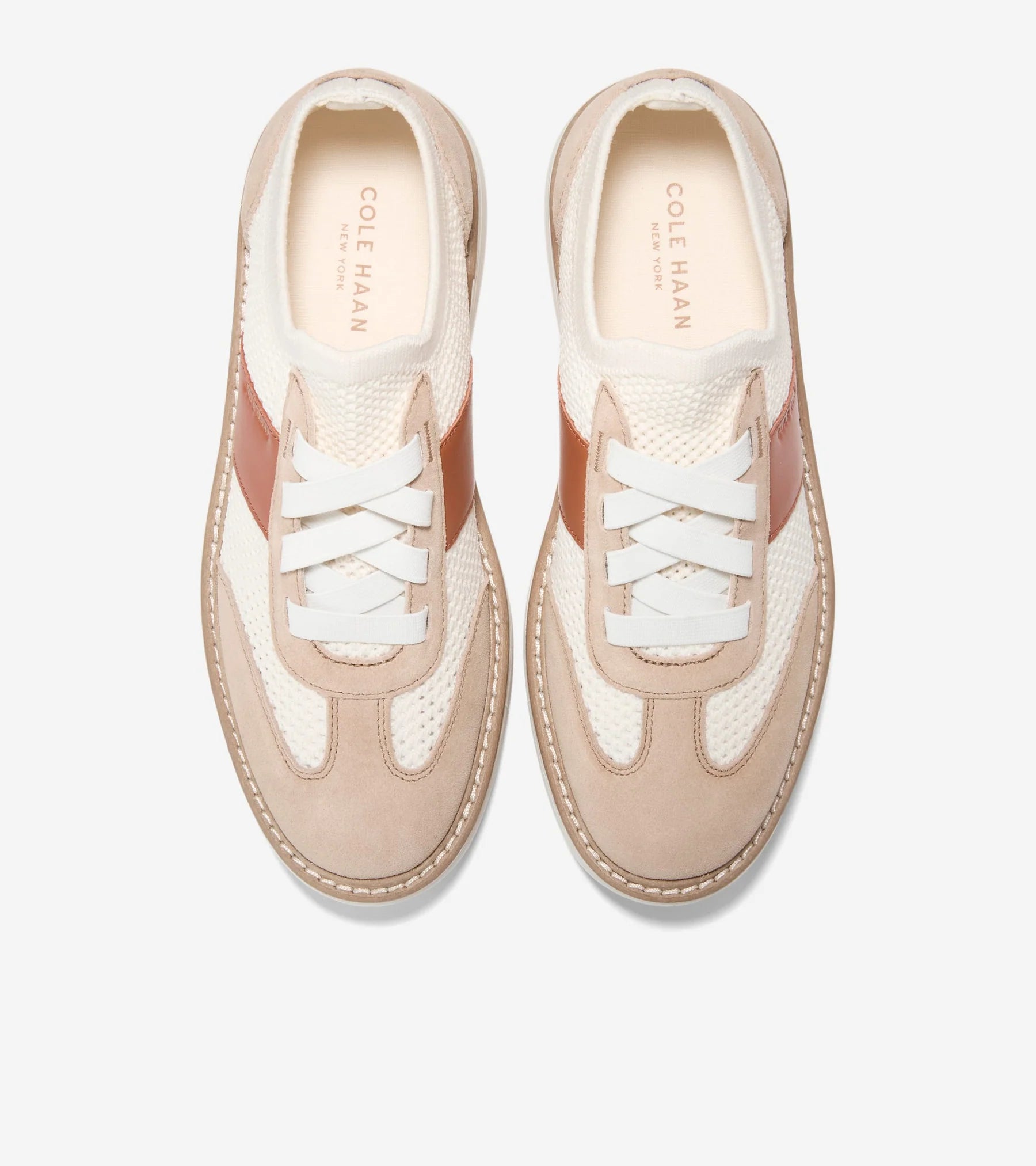 Pair of beige sneakers with white laces on a light gray background