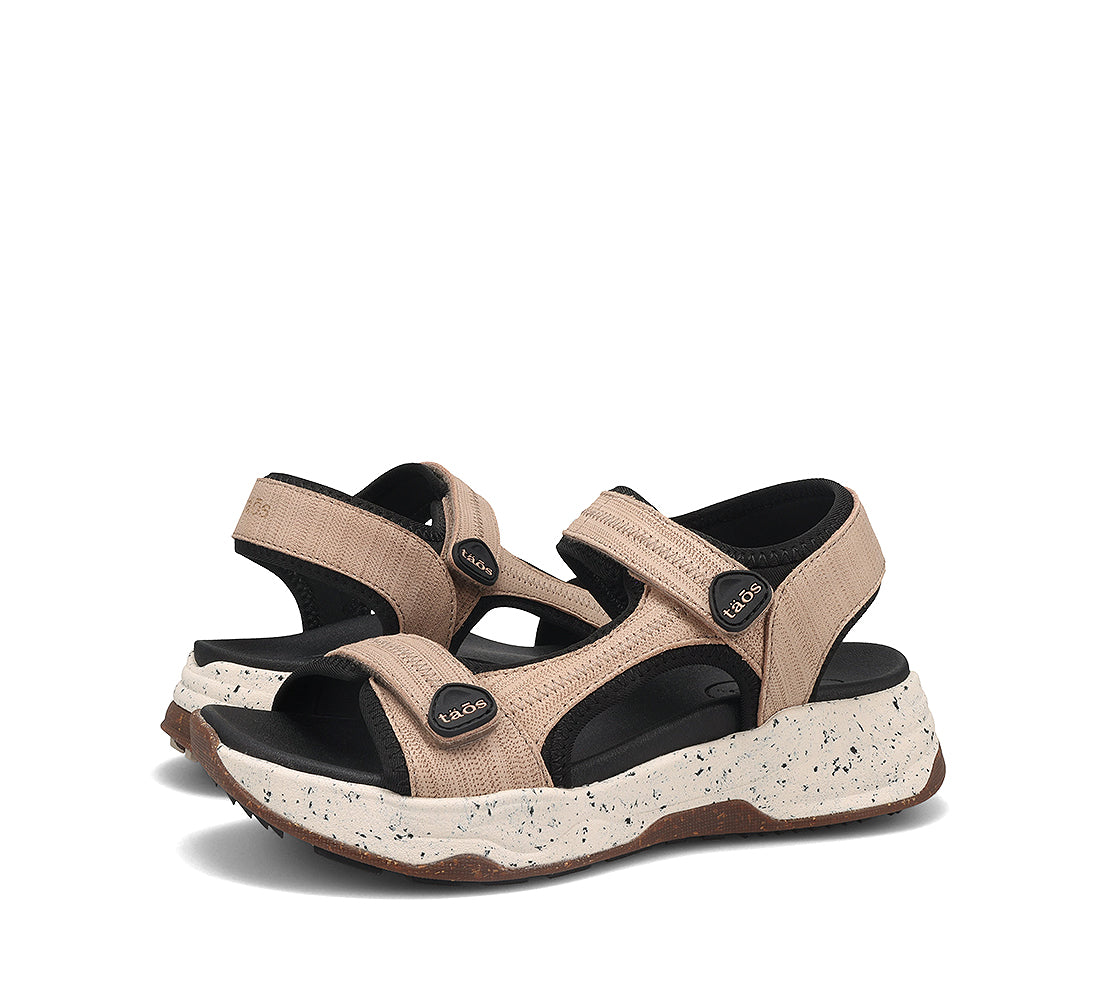 Pair of beige sandals with black soles on a white background