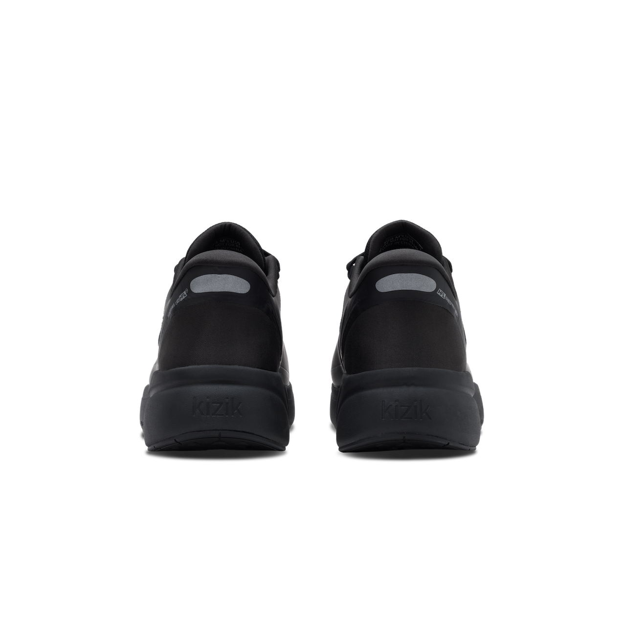 A pair of black low-top sneakers shown from the back, featuring a matte black upper and thick black sole with a small gray reflective accent on the heel.