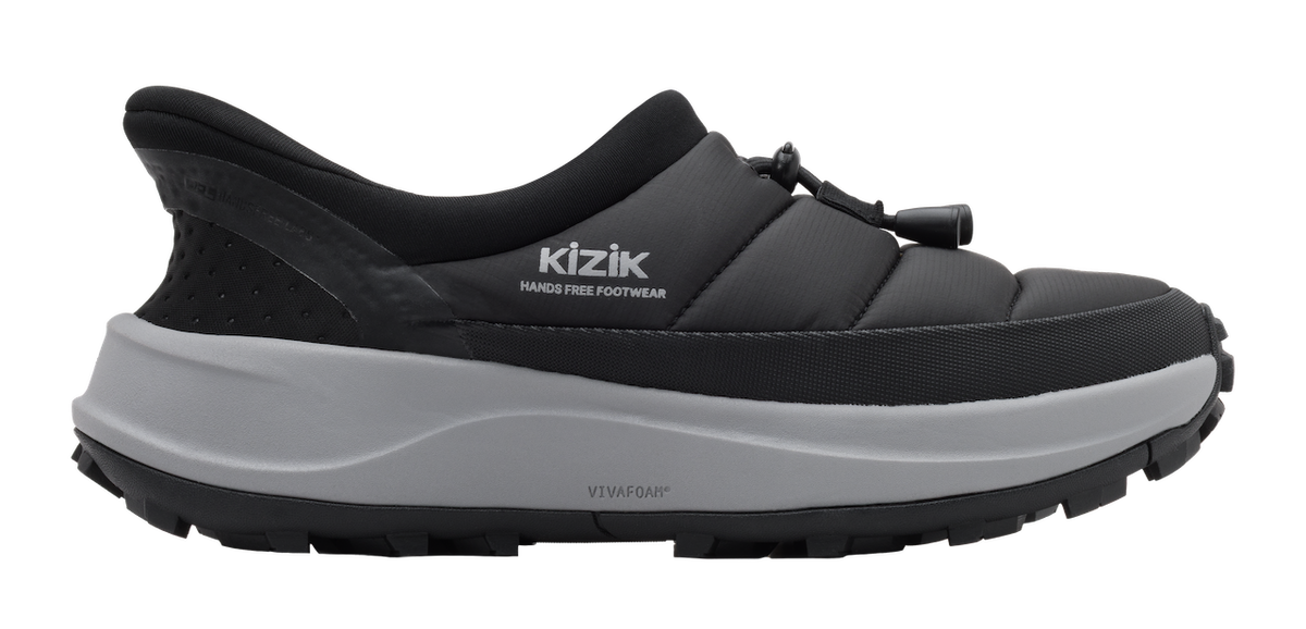 A black Kizik HANGS FREE FOOTWEAR slip-on shoe with a thick gray midsole and black treaded outsole, shown from a side profile on a white background.