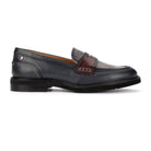A dark navy blue leather penny loafer shoe with a contrasting dark brown leather strap detail across the vamp, shown in a side profile view against a plain white background.