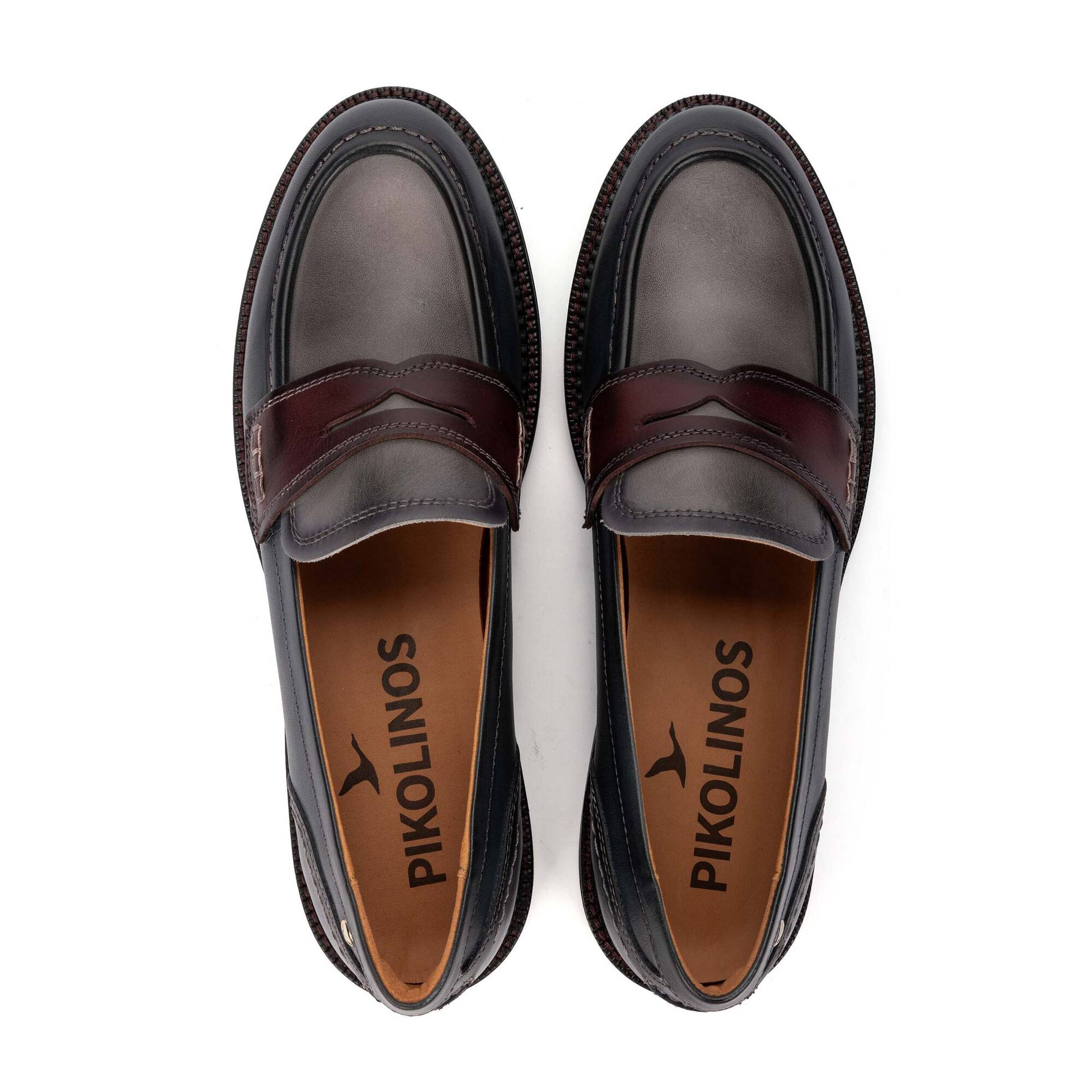 A pair of dark brown leather penny loafers with a darker burgundy strap, shown from a top-down view on a white background. The brand name 'PIKOLINOS' is printed on the tan insoles.