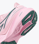 Pink running shoe with green sole on a white background