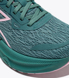 Close-up of a green athletic shoe with pink accents on a white background