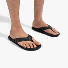Black sandals worn by a person on a white background