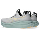 Gray running shoe with green sole on a white background