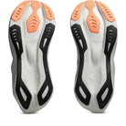 A pair of athletic shoe soles shown from the bottom, featuring a white and gray base with black sculpted side supports and bright orange protective toe sections.