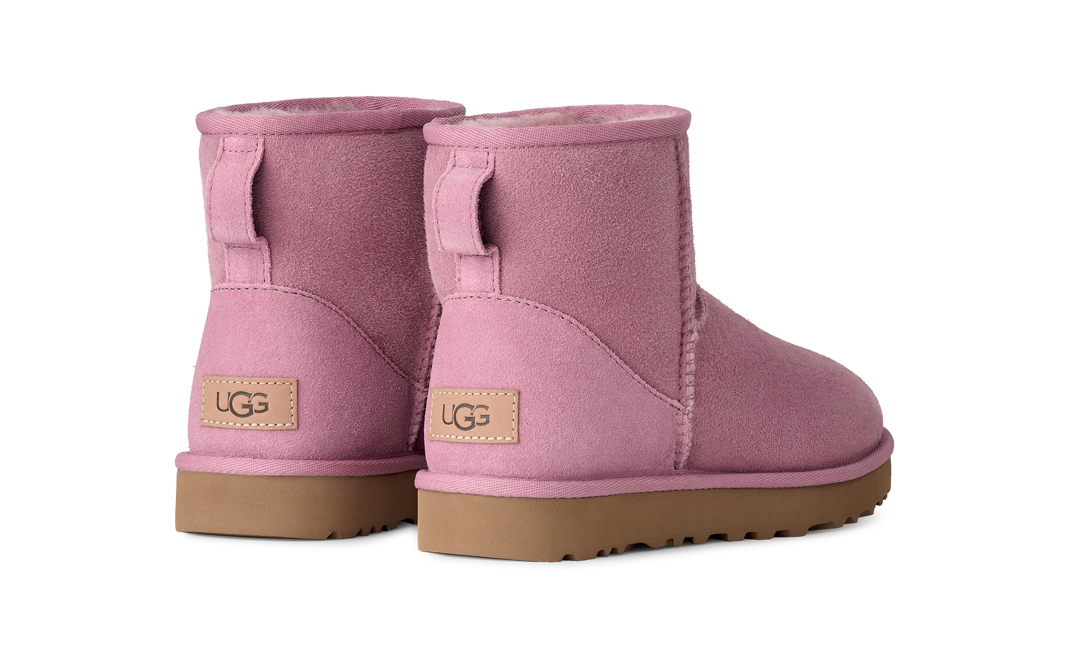 A pair of UGG mini boots in dusty pink suede with tan soles, shown from the back on a clean white background.