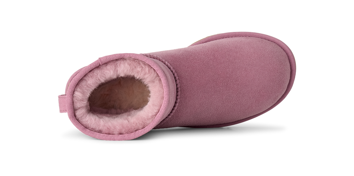 A single dusty pink suede ankle boot with a plush pink shearling lining, shown from a side profile view on a white background.