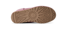 The bottom sole of a pink shoe, showing a textured brown rubber tread with a circular sunburst pattern and a small UGG logo embossed on the heel.