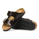 Pair of black crocodile-patterned sandals with cork soles on a white background